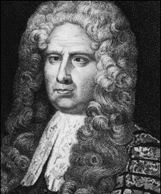 A middle-aged, slightly overweight man. He has long, curled hair, possibly a wig, and a heavy, decorated robe.