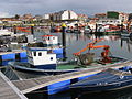 Outro barco no mesmo porto, co guindastre e cesto antigos.