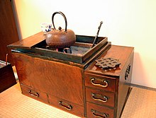 A small cabinet with a grill and pot on top