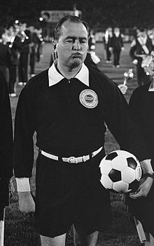 Black and white photo of a man in black with a white football.