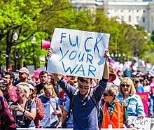 Sarong protester kapotkapot an sarong cardboard sign na nababasa na "FUCK YOUR WAR"