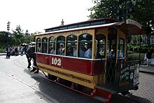 A red and white enclosed horse-drawn streetcar hitched to a draft horse