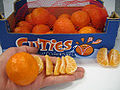 Box of Clementines with hand for size reference.