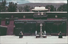 Le temple principal du monastère de Nechung, avec au premier plan un pilier et deux brûleurs d'encens, et au second plan deux pierres sculptées en forme de lion, photo datant d'avant 1950.