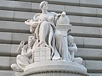 Marble statue of a seated woman leaning on a globe