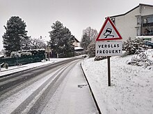 Une route enneigée avec le panonceau verglas fréquent