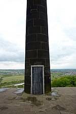 A door in a stone column, covered with a metal grate