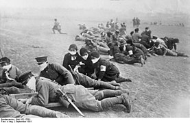 Photographie d'une unité d'infanterie pendant un exercice. Aux côtés des soldats, des infirmières sont visibles.