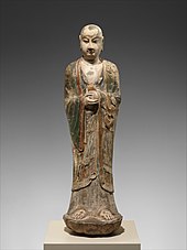 Colored limestone sculpture of monk holding an unidentified object