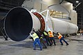 Several workers rotate an SRMU, pushing on its aft end.