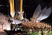 Faraway image of Madonna on a golden throne being carried by a number of bearers.