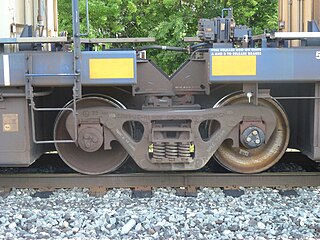 Closeup of a truck with four specially adapted side bearings and an articulated connector between two sections of an articulated well car