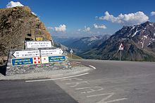 A road summit hairpin with mountains in the background