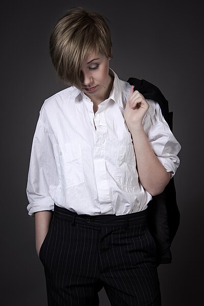 File:Woman in white shirt and black trousers looking down.jpg