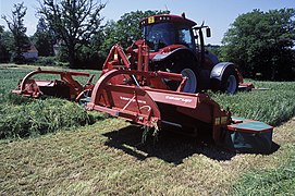 Ensemble faucheur-conditionneur à trois corps à disques mu par un tracteur d'environ 200 ch