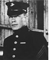 Head and shoulders of square-jawed man in circa 1920 formal U.S. Marine uniform.