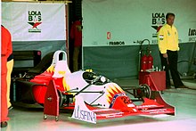 Photo des stands de la Scuderia Italia, avec un châssis rouge, jaune et blanc