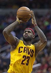 A black player with ball in hand, preparing to shoot the basketball.