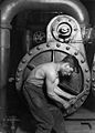 Image 14Lewis Hine's 1920 image "Power house mechanic working on steam pump," which shows a working class young American man with wrench in hand, hunched over, surrounded by the machinery that defines his work.