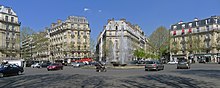 Photographie en couleurs, représentant une Place et des bâtiments (la place Victor-Hugo).