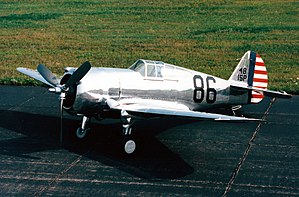 Shiny metal single-engine propeller-driven aircraft on a tarmac.