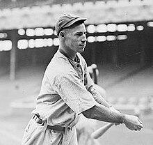 Snapshot of a man in a baseball uniform, just finishing swinging his bat during practice.