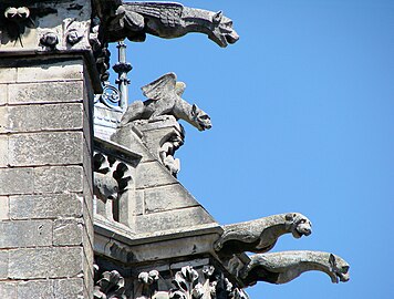 Au centre, le félin à ailes de chauve-souris, juché au sommet d'un contrefort sur un piédestal soutenu par un sympathique corbeau, est une chimère et non pas une gargouille. En contrebas on voit plusieurs gargouilles situées au niveau de la partie déclive de la galerie qui court à gauche. (Chevet de la cathédrale, toiture de la chapelle rayonnante du Sacré-Cœur).