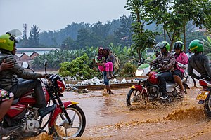 Bodabodas und Fußgänger auf einer überfluteten Straße in Kigali