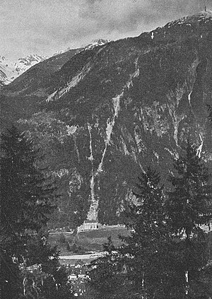 Blick von der rechten Reusstalseite oberhalb Amsteg auf die Zentrale und die Druckleitung des Kraftwerks Arniberg. Der Pfeil weist auf die ungefähre Lage des Arnisees hin.