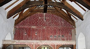 Red-painted wooden screen across the inside of a church, with a painted cross