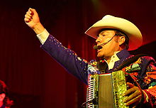 A man holding an accordion performs in the front of the audience.