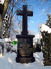 Photographie en couleur de la tombe de Schleyer : crucifix surmontant une large base, ornée d'un ciboire et présentant une longue épitaphe en volapük.