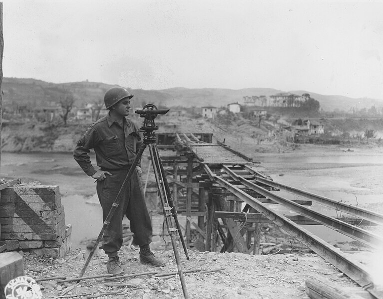 File:SC 337245 - S Sgt. Robert E. Sause with a engr. construction outfit about to take a level at the sighting position where he will survey for the construction of a new bailey bridge over the Reno River. (52211107088).jpg