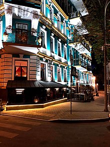 A three-story turquoise and gold building on a street corner