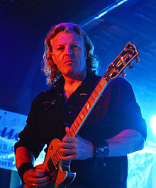 Roland Grapow playing guitar, looking at camera