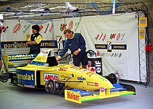 Photo d'une monoplace jaune dans un garage.