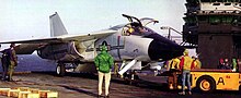 An F-111B on the deck of an aircraft carrier being towed.