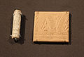 A cylinder seal made out of glazed soapstone discovered in Tutub (dated to c. 3100 – c. 2900 BCE) to the left of a modern, clay seal impression.