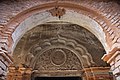 Hindu religious inscription on stucco relief under a Mughal-style arch.