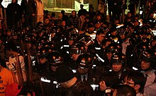 A tightly bundled group of police officers in riot gear assembled in Jackson Road