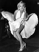 Marilyn Monroe posing for photographers in a white dress during production of The Seven Year Itch