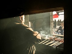 Seorang lelaki memanggang daging untuk jemaah.