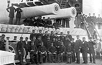 Admiral Felice Napoleone Canevaro and the officers of Italia pose under a pair of her 17-inch (432-mm) guns.