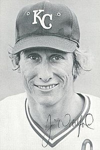 A man in a light baseball uniform and dark hat