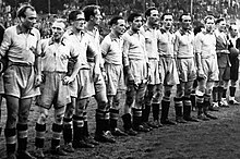 Photographie d'une équipe de football vue de trois-quarts au maillot blanc. Les joueurs sont alignés.