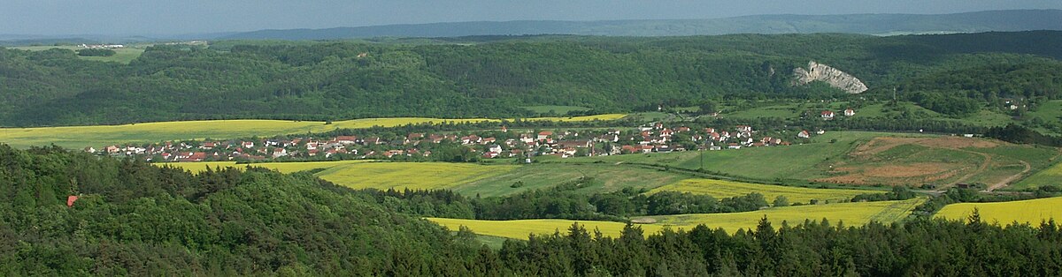 Pohled na Vráž směrem od severu na jih, foceno z rozhledny nad obcí Lhotka u Berouna. V pozadí obrázku vyčnívá Svatojánská skála, dominanta nad obcí Svatý Jan pod Skalou