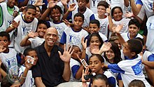 Kareem Abdul-Jabbar saluant l'objectif, au milieu d'enfants.