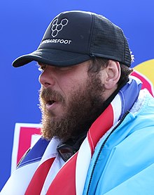 A man with a beard and mustache wearing a cap and a thick jacket