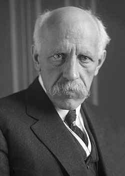 Head and shoulders portrait of Fridtjof Nansen, facing half-right. He has close-cropped hair, a wide, fair moustache and is wearing a heavy fur coat.