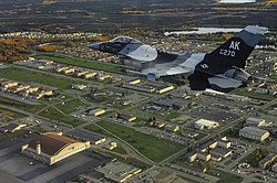 An F-16C Fighting Falcon from the 18th Aggressor Squadron flies over Eielson AFB in 2009. The base's largest hangar, known as the "Thunderdome," is visible in the bottom left of the image.